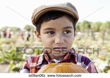 Portrait of boy looking sideways and holding pumpkin in pumpkin field View Large Photo Image Stock Photo - Portrait of boy looking sideways and holding pumpkin in pumpkin field. Fotosearch