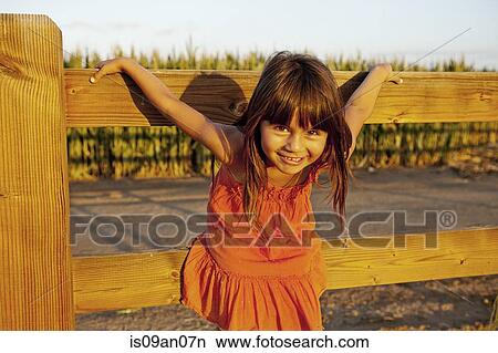 Portrait of girl holding onto wooden fence View Large Photo Image Picture - Portrait of girl holding onto wooden fence. Fotosearch