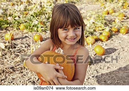 Portrait of girl holding pumpkin in pumpkin field View Large Photo Image Picture - Portrait of girl holding pumpkin in pumpkin field. Fotosearch