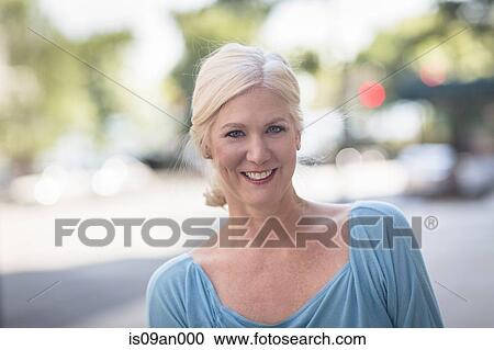 Stock Image - Portrait of mature woman on sunlit street. Fotosearch