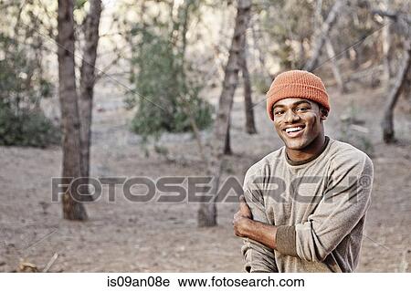 Stock Image - Portrait of smiling young man in forest. Fotosearch