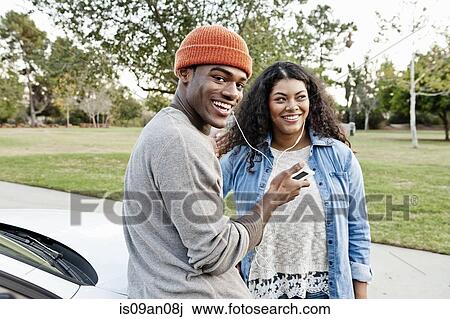 Portrait of young couple in car park sharing smartphone music View Large Photo Image Stock Image - Portrait of young couple in car park sharing smartphone music. Fotosearch