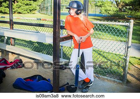 Stock Photo - "Portrait of young girl wearing baseball kit, standing with baseball bat". Fotosearch