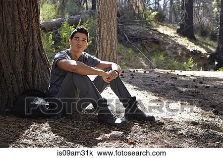 Stock Image - "Portrait of young man sitting in forest, Los Angeles, California, USA". Fotosearch