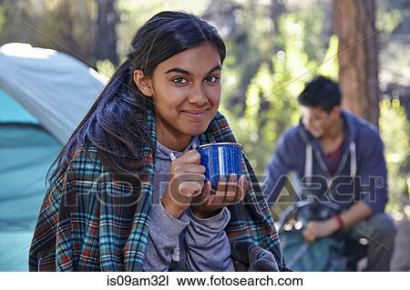 Stock Image - "Portrait of young woman drinking coffee in forest, Los Angeles, California, USA". Fotosearch