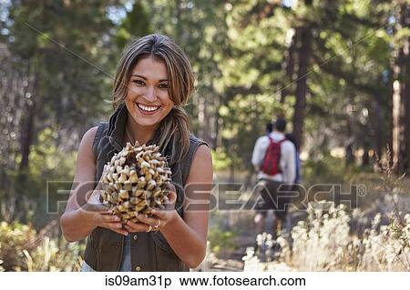 "Portrait of young woman in forest holding large pine cone, Los Angeles, California, USA" View Large Photo Image Stock Photography - "Portrait of young woman in forest holding large pine cone, Los Angeles, California, USA". Fotosearch
