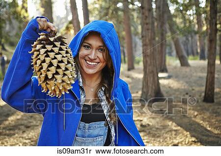 "Portrait of young woman in forest holding up large pine cone, Los Angeles, California, USA" View Large Photo Image Stock Photography - "Portrait of young woman in forest holding up large pine cone, Los Angeles, California, USA". Fotosearch
