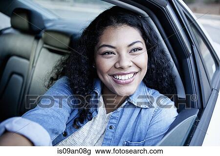 Stock Image - Portrait of young woman looking out of car window. Fotosearch