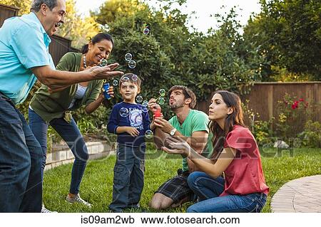 Three generation family blowing bubbles in garden View Large Photo Image Stock Image - Three generation family blowing bubbles in garden. Fotosearch