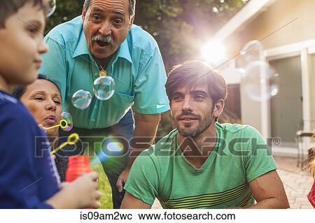 Three generation family blowing bubbles in garden View Large Photo Image Stock Image - Three generation family blowing bubbles in garden. Fotosearch
