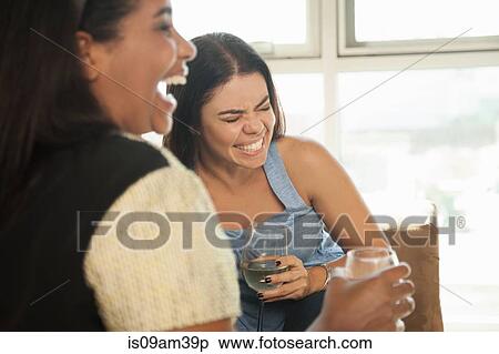 Stock Photography - "Two female friends sitting on sofa, drinking wine". Fotosearch