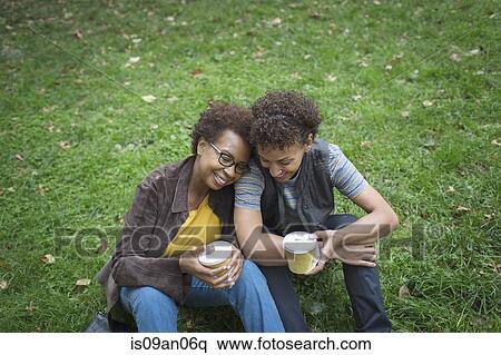 Stock Photography - Two mature female friends drinking takeaway coffee in park. Fotosearch