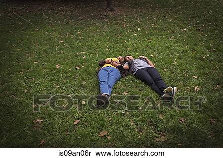 Two mature female friends lying on park grass head to head View Large Photo Image Stock Photography - Two mature female friends lying on park grass head to head. Fotosearch