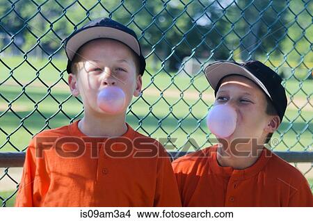 Picture - Two young male baseball players blowing bubbles with bubblegum. Fotosearch