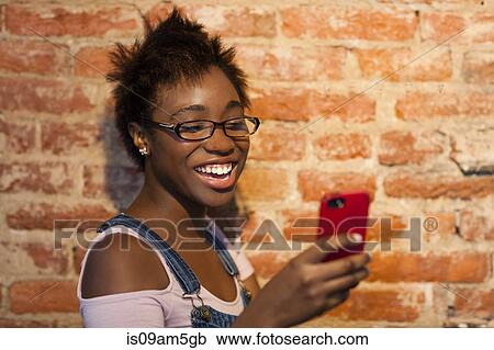Woman using smartphone by brick wall View Large Photo Image Stock Image - Woman using smartphone by brick wall. Fotosearch