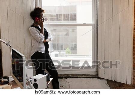 "Woman using smartphone by window, home office" View Large Photo Image Stock Photo - "Woman using smartphone by window, home office". Fotosearch