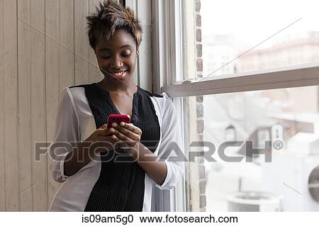 Woman using smartphone by window View Large Photo Image Stock Image - Woman using smartphone by window. Fotosearch