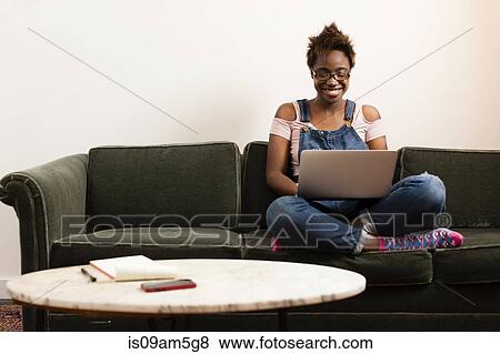 Woman working at laptop on sofa View Large Photo Image Stock Photo - Woman working at laptop on sofa. Fotosearch