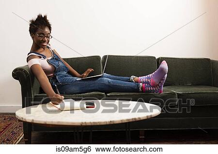 Woman working at laptop on sofa View Large Photo Image Stock Photograph - Woman working at laptop on sofa. Fotosearch