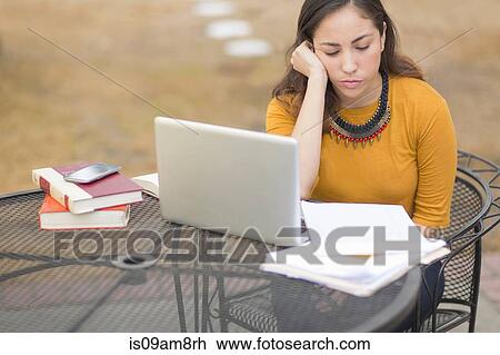 Stock Image - "Women working, reading and using laptop outdoors". Fotosearch