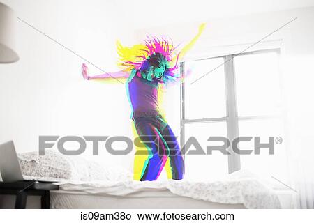 Picture - Young Asian woman dancing on bed. Fotosearch
