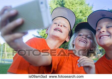 Stock Image - Young baseball players taking self portrait using smartphone. Fotosearch