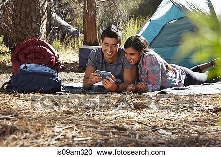 "Young camping couple looking at smartphone in forest, Los Angeles, California, USA" View Large Photo Image Stock Image - "Young camping couple looking at smartphone in forest, Los Angeles, California, USA". Fotosearch