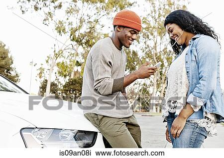 Young couple in car park sharing smartphone music View Large Photo Image Stock Image - Young couple in car park sharing smartphone music. Fotosearch