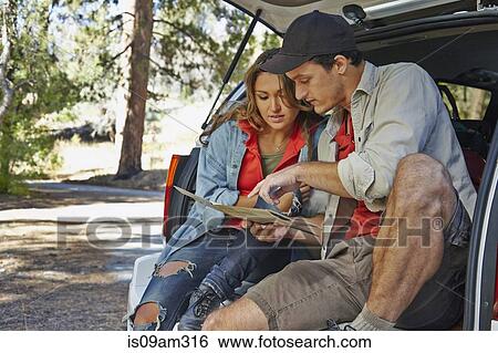 "Young couple sitting on car boot pointing at map, Los Angeles, California, USA" View Large Photo Image Stock Photograph - "Young couple sitting on car boot pointing at map, Los Angeles, California, USA". Fotosearch