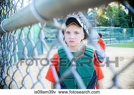 "Young girl wearing baseball kit, looking through fence" View Large Photo Image Stock Photo - "Young girl wearing baseball kit, looking through fence". Fotosearch