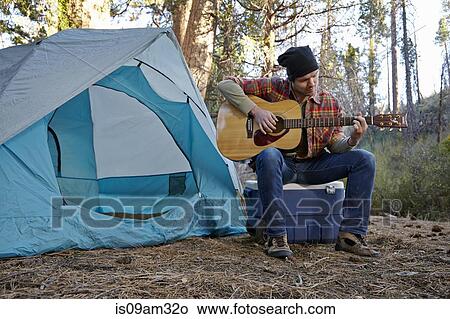 "Young male camper playing guitar in forest, Los Angeles, California, USA" View Large Photo Image Picture - "Young male camper playing guitar in forest, Los Angeles, California, USA". Fotosearch