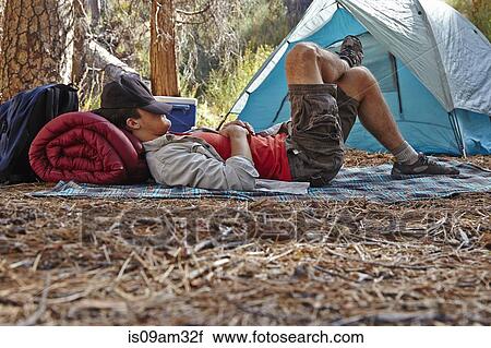 Stock Image - "Young male camper resting in forest, Los Angeles, California, USA". Fotosearch