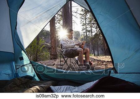 Stock Photography - "Young male camper using digital tablet in forest, Los Angeles, California, USA". Fotosearch