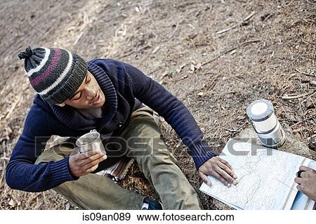 "Young man with mug, looking at map outdoors" View Large Photo Image Stock Photo - "Young man with mug, looking at map outdoors". Fotosearch