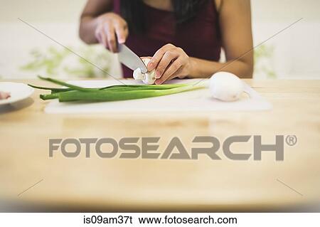 Stock Photograph - "Young woman slicing mushroom, mid section". Fotosearch