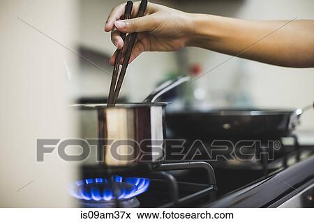 Young woman stirring pan on cooker top with chopsticks View Large Photo Image Stock Photo - Young woman stirring pan on cooker top with chopsticks. Fotosearch