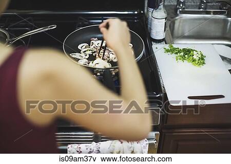 "Young woman stirring sliced mushrooms in frying pan, rear view" View Large Photo Image Stock Photo - "Young woman stirring sliced mushrooms in frying pan, rear view". Fotosearch