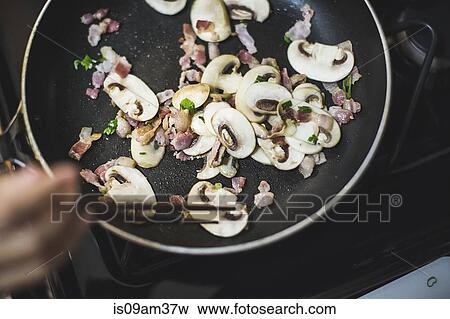 "Young woman stirring sliced mushrooms in frying pan, overhead view" View Large Photo Image Stock Photo - "Young woman stirring sliced mushrooms in frying pan, overhead view". Fotosearch