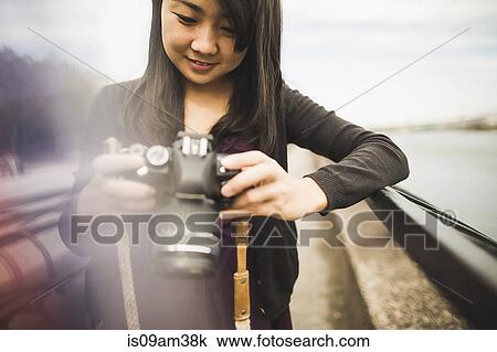 Stock Image - "Young woman taking photographs, outdoors". Fotosearch