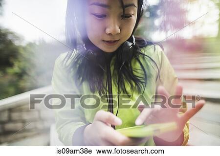 "Young woman using mp3 player, wearing headphones, outdoors" View Large Photo Image Stock Image - "Young woman using mp3 player, wearing headphones, outdoors". Fotosearch