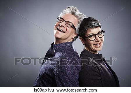 Stock Photograph - Back to back studio portrait of mature businessman and woman. Fotosearch
