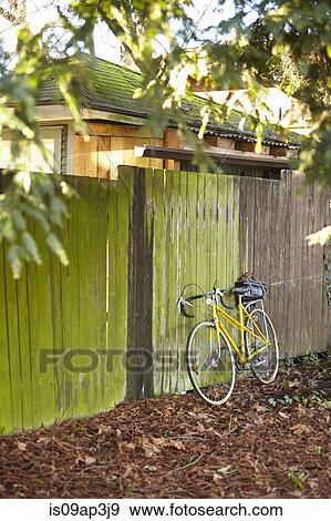 Bicycle leaning against fence View Large Photo Image Stock Photo - Bicycle leaning against fence. Fotosearch