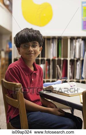 Picture - Boy looking away from book in classroom. Fotosearch
