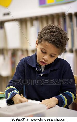 Stock Image - Boy writing in classroom. Fotosearch