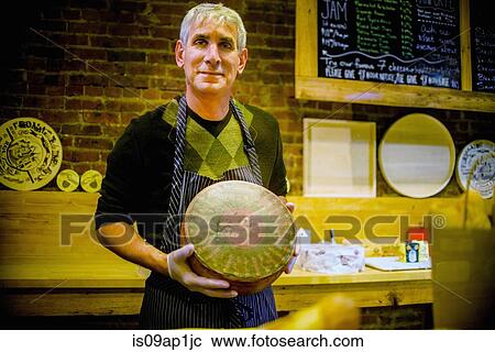 Cheesemonger holding wheel of cheese View Large Photo Image Stock Image - Cheesemonger holding wheel of cheese. Fotosearch
