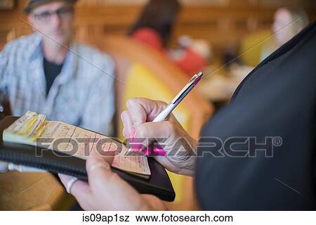 Stock Photo - Cropped close up of waitress writing order on notepad in diner. Fotosearch