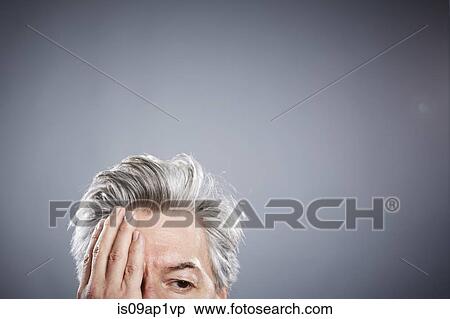 Stock Photography - Cropped studio portrait of mature businessman with hand covering eye. Fotosearch