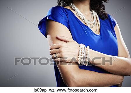Stock Photo - Cropped studio shot of mature woman with arms folded. Fotosearch