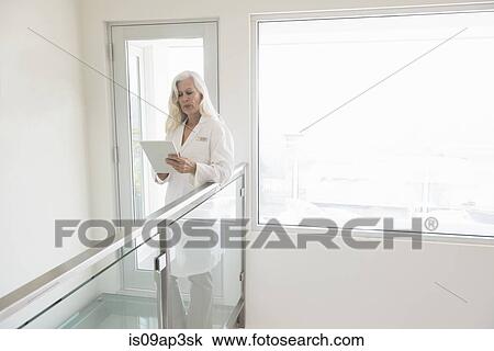 Doctor using digital tablet in corridor View Large Photo Image Stock Image - Doctor using digital tablet in corridor. Fotosearch