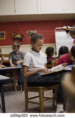 "Girl reading book in classroom, children in background" View Large Photo Image Stock Photography - "Girl reading book in classroom, children in background". Fotosearch